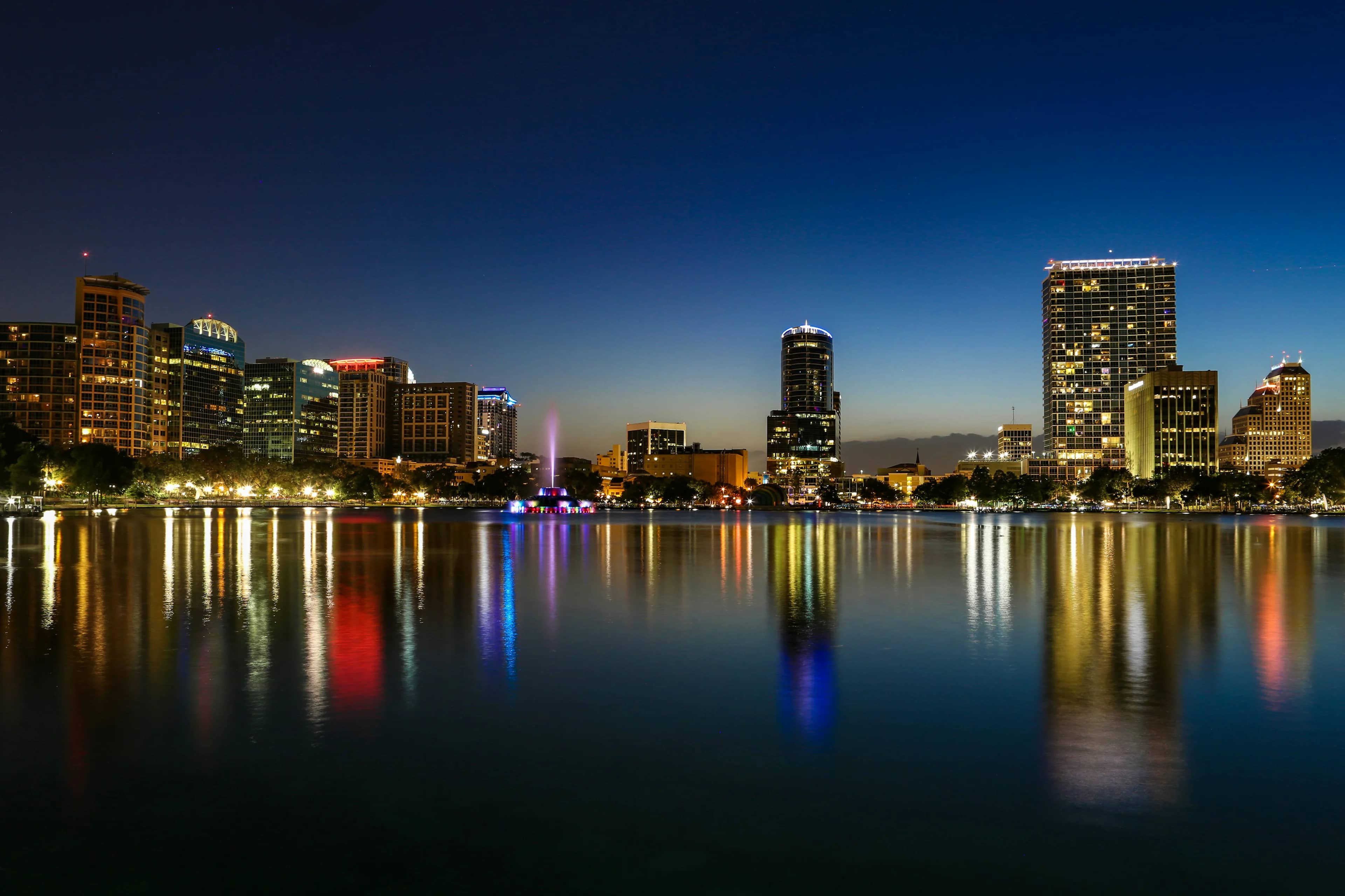 City skyline reflected across a calm lake at night